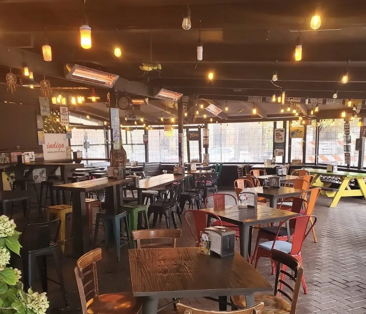 Indigo's covered patio dining room, mismatched tables and chairs under strings of warm bulbs