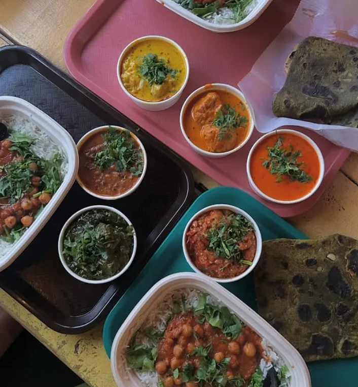 Trays of curries, rice bowls and spinach paratha set out on the patio tables
